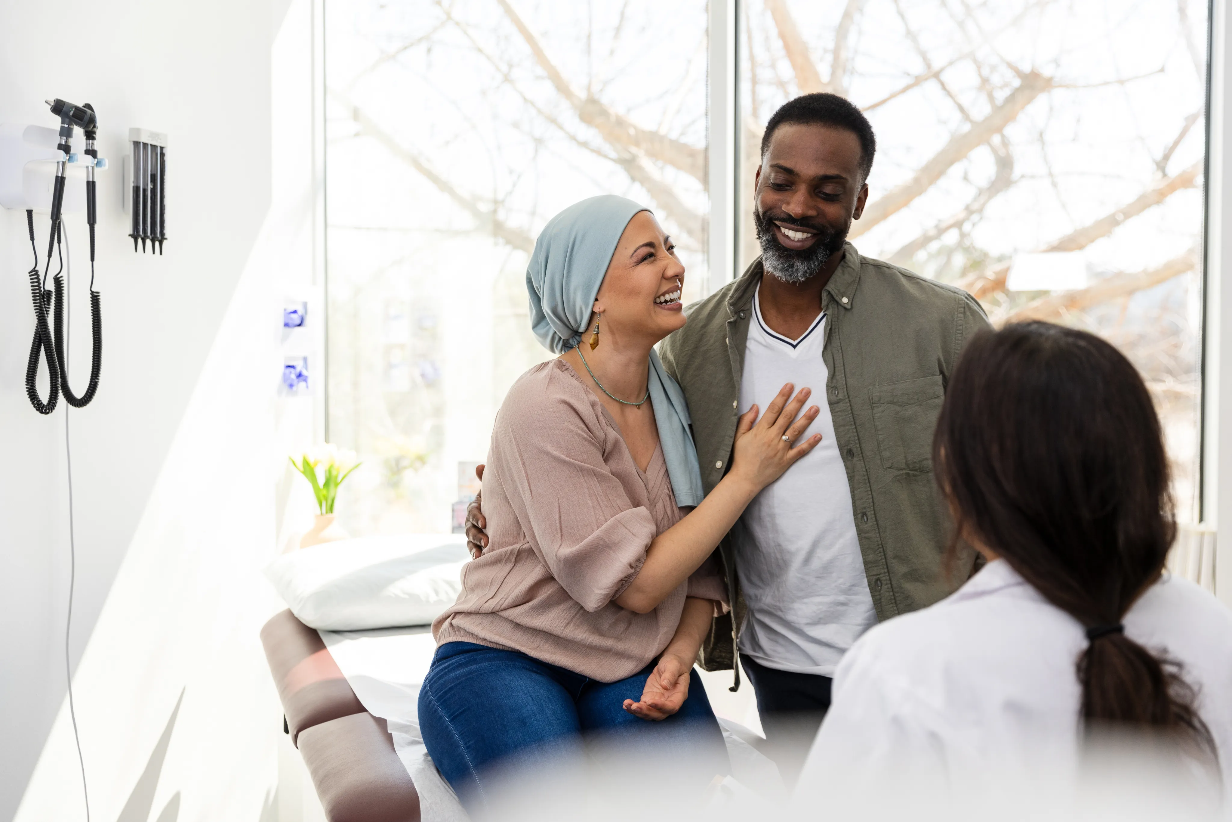 A woman wearing a head scarf smiles up at her partner as he rests a hand on her shoulder.