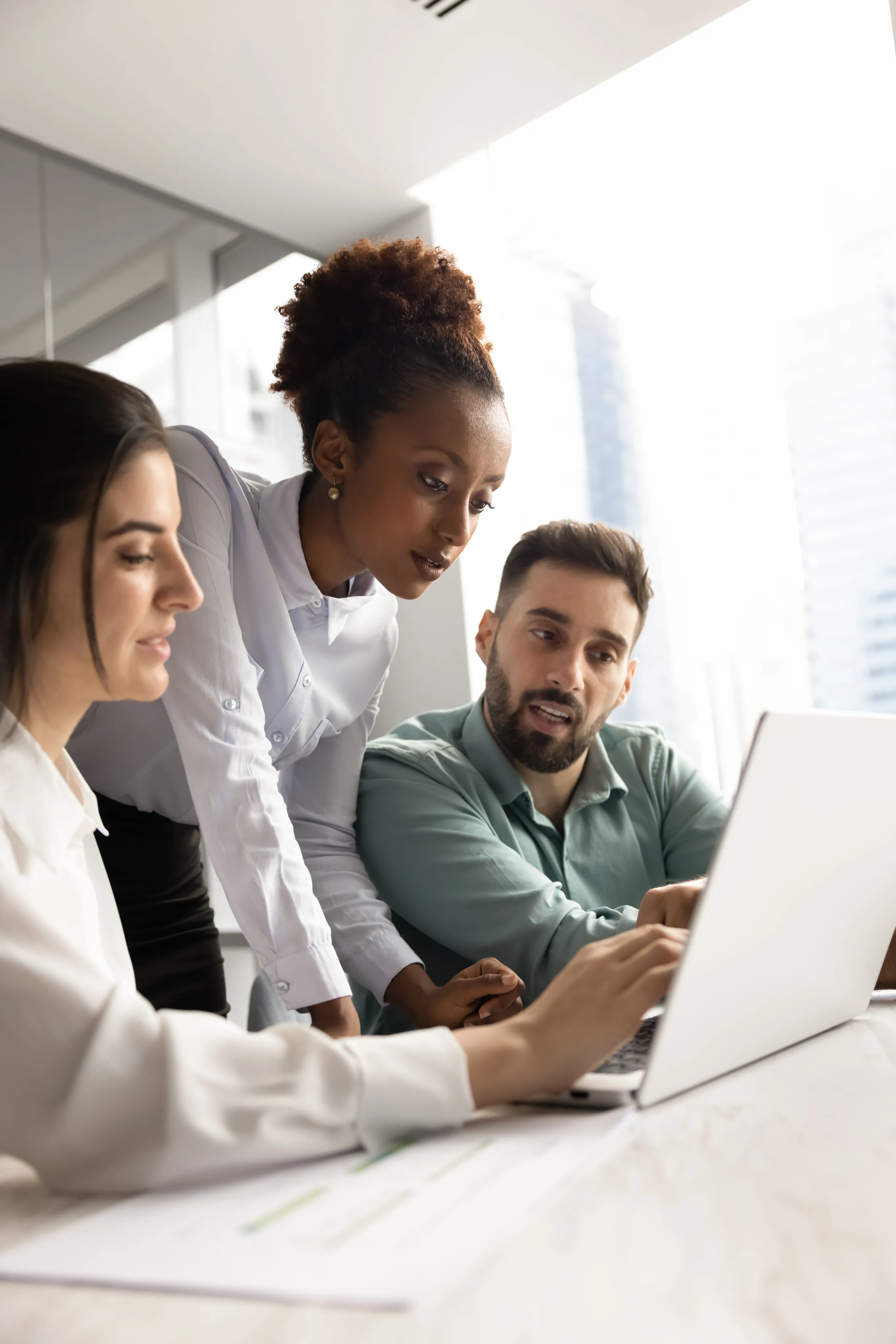 Three colleagues reviewing plan costs together on a laptop