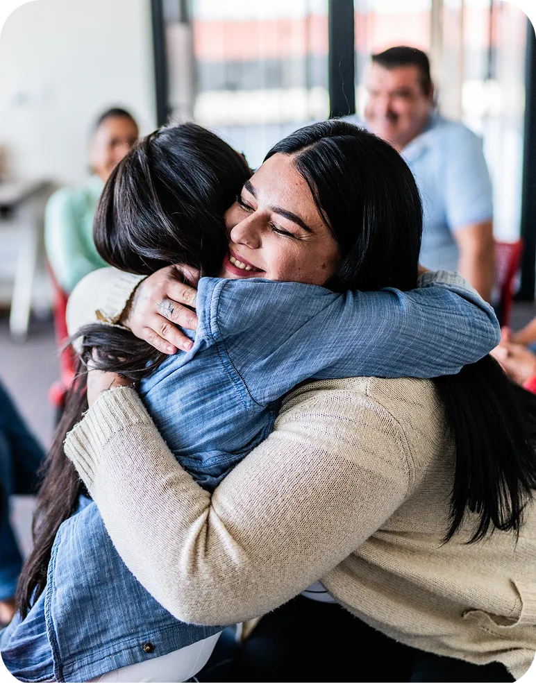 Two women sharing an embrace during a group support meeting