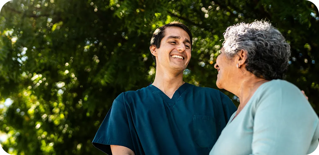 A healthcare worker talking warmly with a patient outdoors